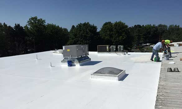 Professional roofers applying a roof coating in Franklin's commercial building